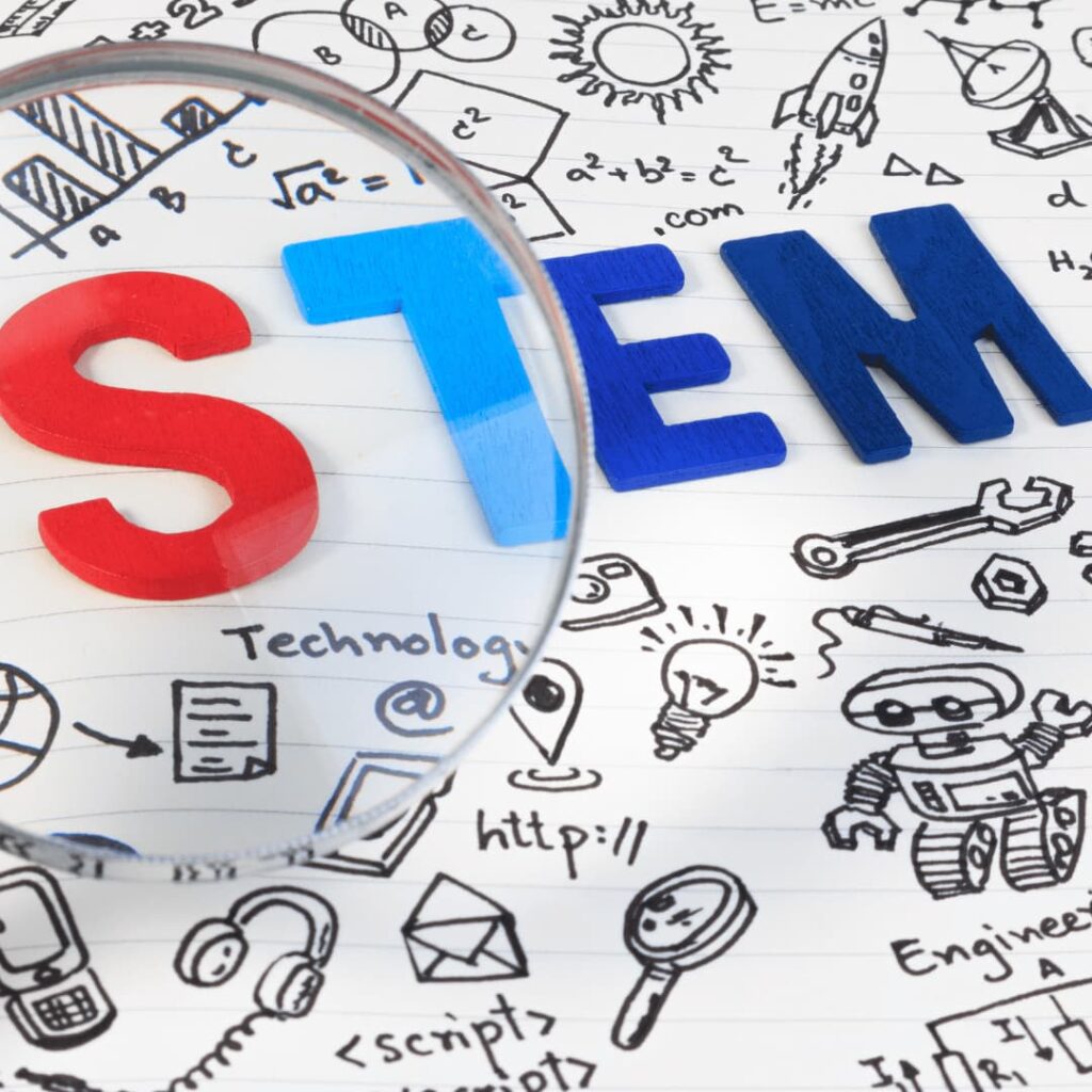 The word "STEM" written on a notepad, with doodles of science and technology-related symbols around it, representing STEM workbooks creation services.