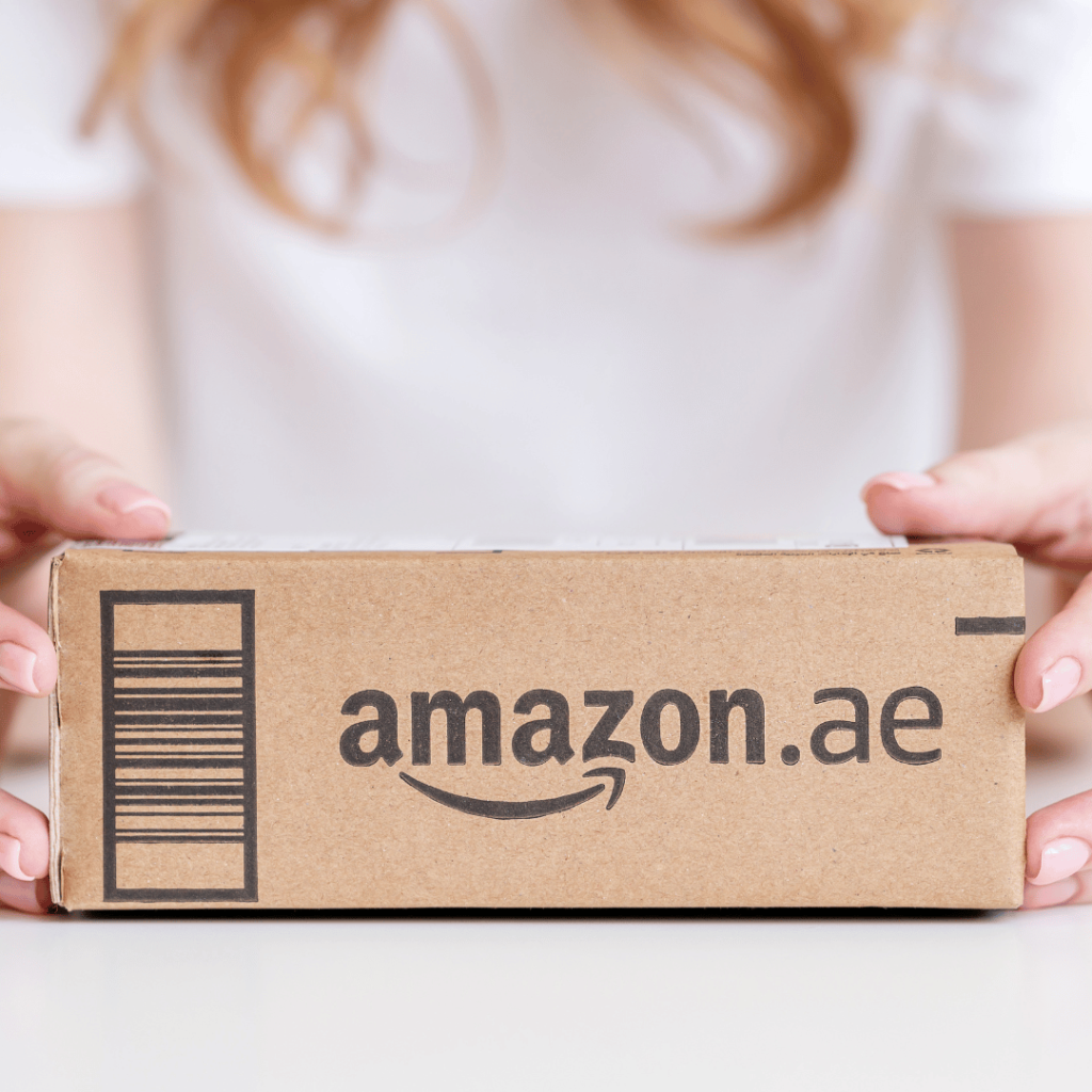 A person holding a cardboard box with the Amazon.ae logo, representing Amazon product description writing services.