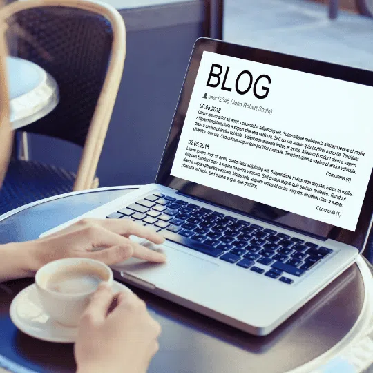 A person holding a coffee cup while viewing a blog on a laptop screen, illustrating the process of crafting engaging blog content, indicating blog writing services.