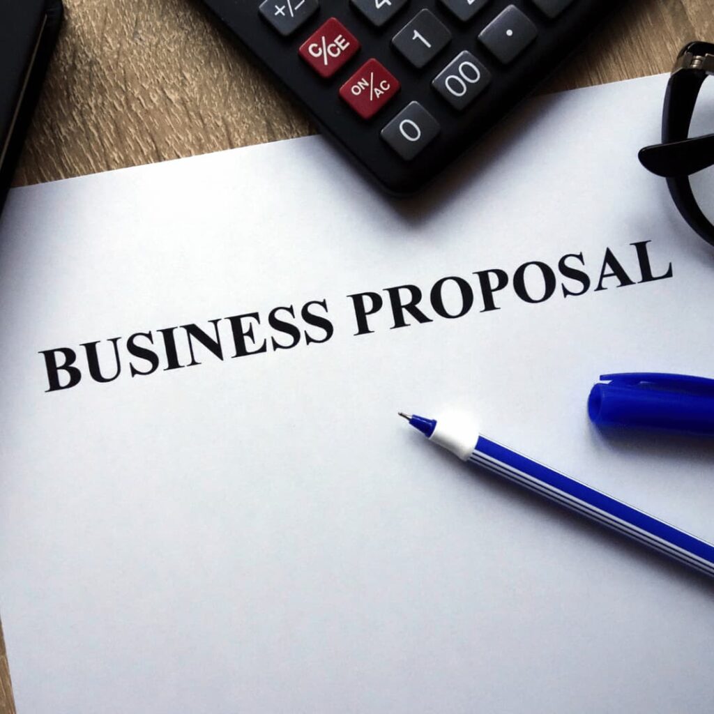 A business proposal document on a desk with a pen, calculator, and glasses, representing business proposal ghostwriting services.