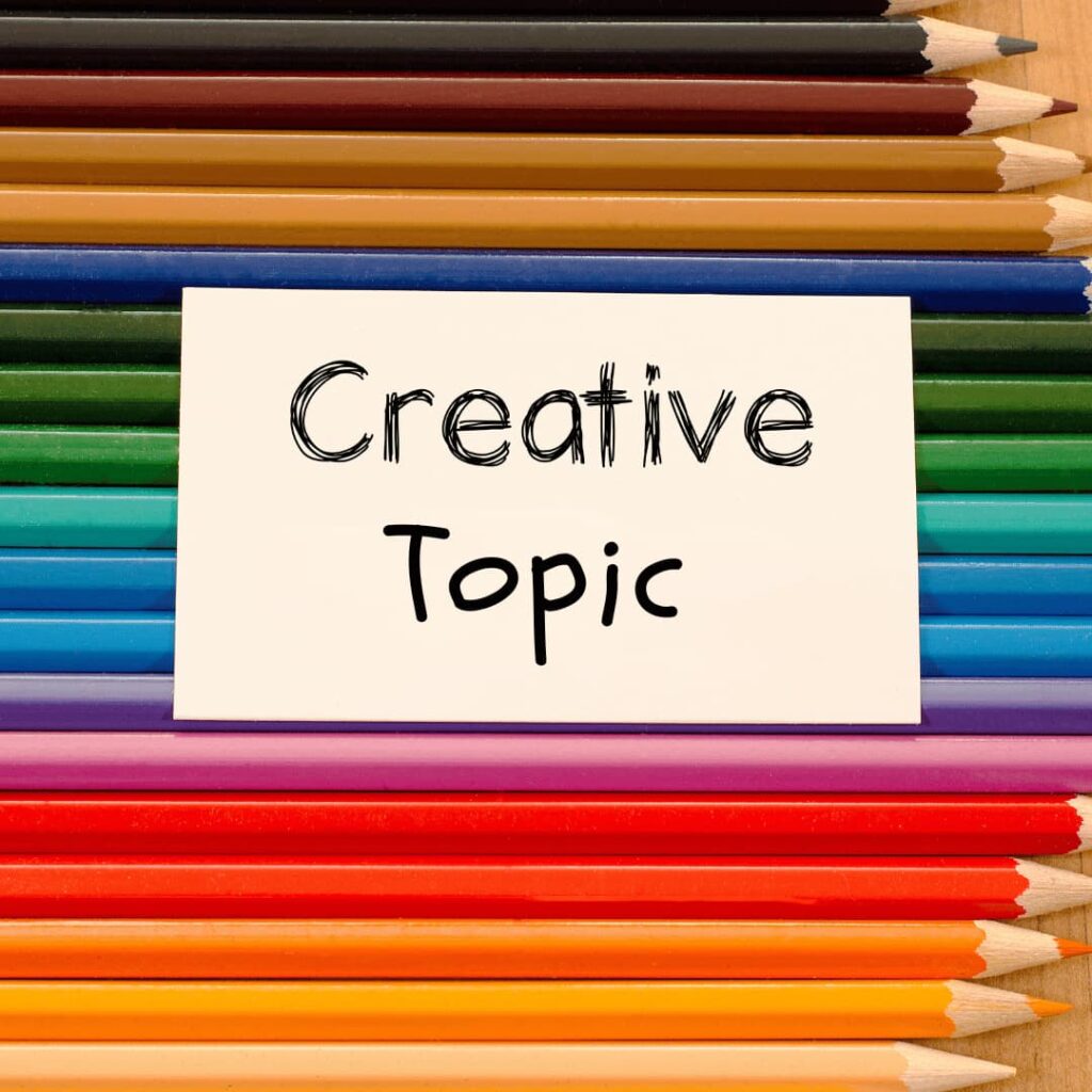 A collection of colorful pencils arranged horizontally with a card in the center that reads 'Creative Topic', indicating creative-topic-ideation for SEO Blog writing services