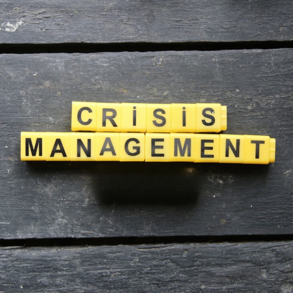 Yellow blocks arranged to spell "Crisis Management" on a dark wooden surface, symbolizing the handling and communication of critical situations, emphasizing the press release writing services for crisis management statements.