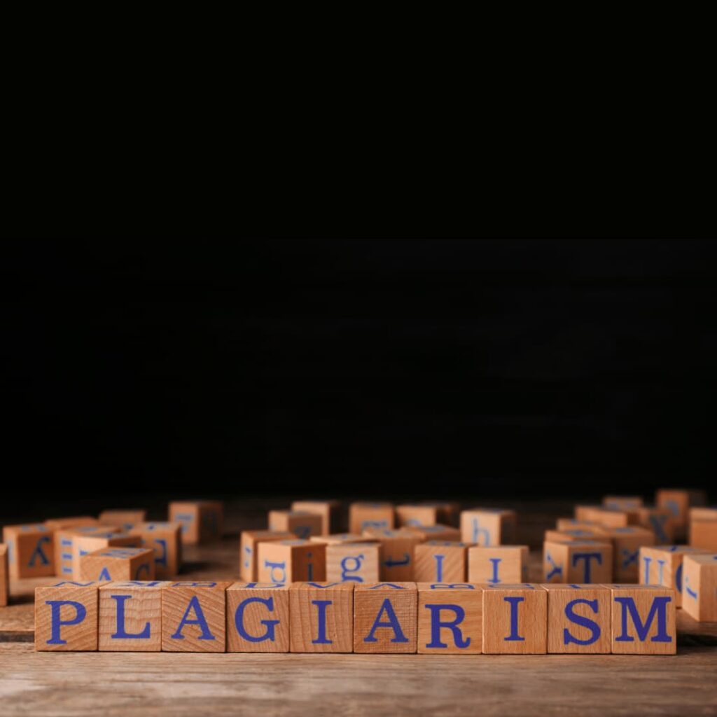 Wooden blocks spelling out "PLAGIARISM" on a dark background, highlighting plagiarism checker services.