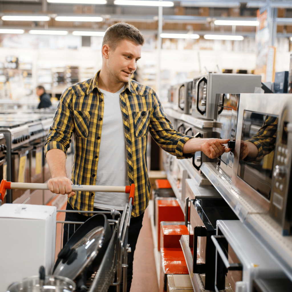 A man in a plaid shirt examining a microwave in an electronics store, representing product description writing services for consumer electronics.