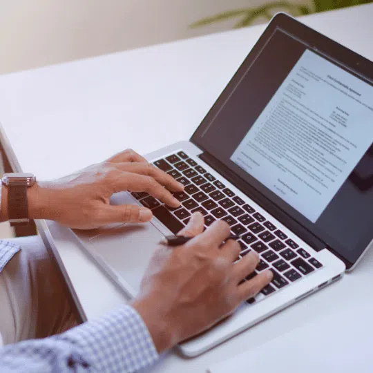 A person working on a laptop with a technical document open, highlighting the expertise involved in technical article writing, indicating technical article writing services.